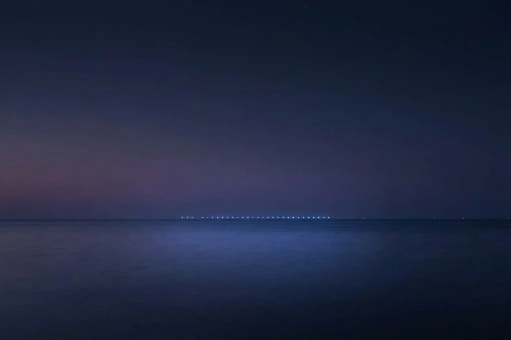 水平線に灯りがともる夜の海。